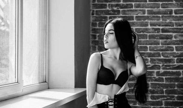 Passionate mysterious lover. Enjoying morning sunlight. Sensual girl sexy breasts relaxing near windowsill. Attractive female lingerie just relaxing at home. Fan of role games. Enjoying her beauty - 写真・画像