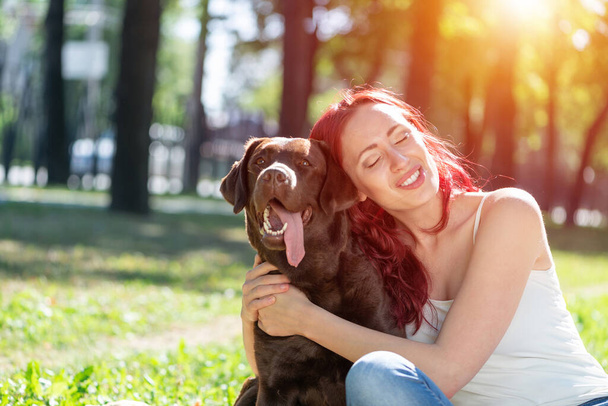 Young attractive woman hugs her dog in the park. - Foto, imagen
