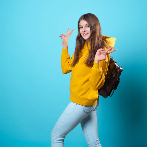 Cute young brunette in jeans and yellow hoodie. A beautiful student - Foto, immagini