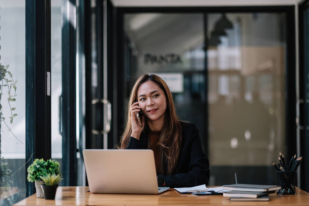 Portret młodej azjatyckiej kobiety freelance online pracującej w domu z laptopem podczas rozmowy telefonicznej. koronawirus kwarantanny, firma rozpoczynająca działalność technologiczną. - Zdjęcie, obraz