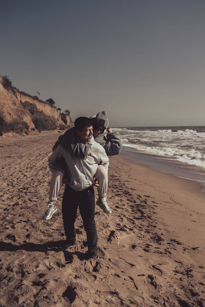 Man draagt zijn vriendin op terug, paar hebben plezier op de kust - Foto, afbeelding