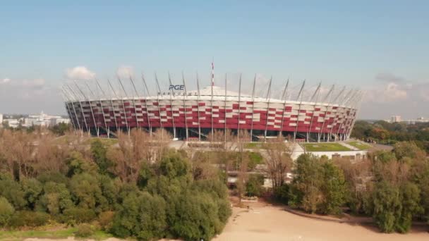 Voe em torno do estádio nacional polonês, moderna arena multifuncional. Vista de baixo ângulo acima das árvores no parque. Varsóvia, Polónia - Filmagem, Vídeo