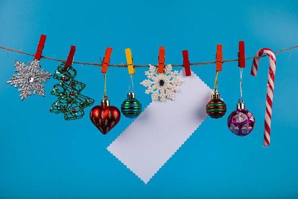 Weihnachtsschmuck hängt an einem Seil auf blauem Grund. Platz für Ihren Text. Weihnachtskarte. - Foto, Bild