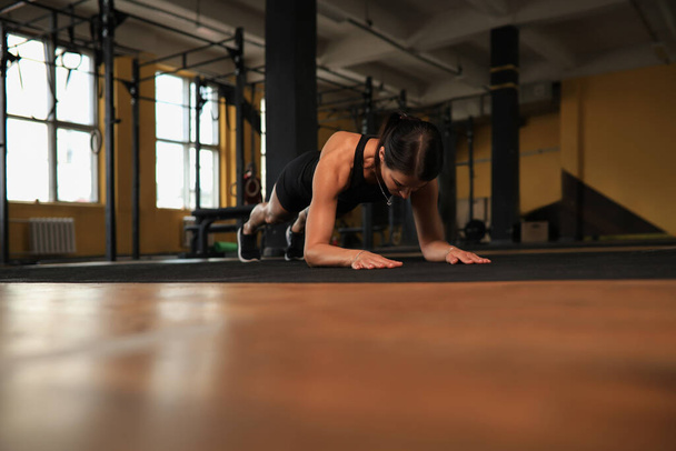 Portrait of a muscular woman on a plank position - Фото, изображение