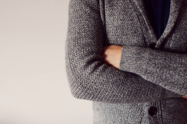 A man with crossed arms in a cardigan on a light background. Copy sapce. - Foto, imagen