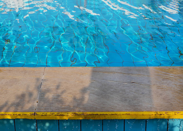 de εστιασμένο πλαίσιο στην πλευρά της πισίνας και το νερό μπλε επιφάνεια του νερού. Καθαρό νερό τρέχει κάτω από τις άκρες της πισίνας - Φωτογραφία, εικόνα
