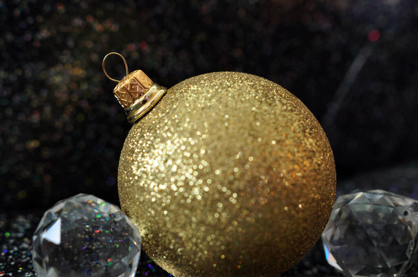 Θολή χριστουγεννιάτικο φόντο, χρυσή λάμψη χριστουγεννιάτικη μπάλα και κρύσταλλα κοντά - Φωτογραφία, εικόνα