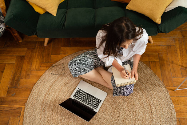 Επιχειρηματίας που εργάζεται σε φορητό υπολογιστή κάθεται στο σπίτι και τη διαχείριση της επιχείρησής της μέσω του γραφείου στο σπίτι - Φωτογραφία, εικόνα