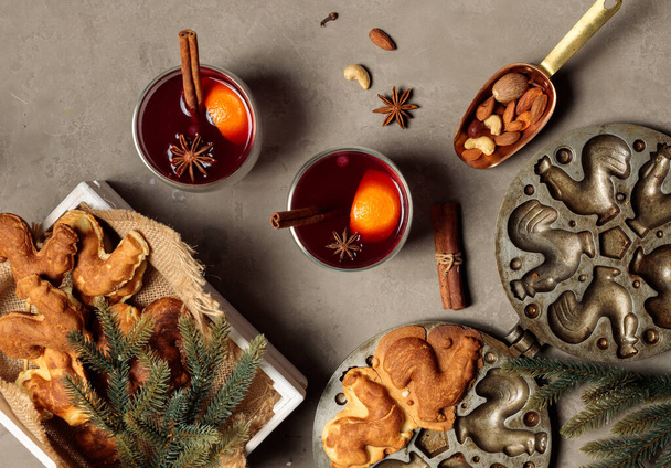 The concept of home winter holidays. Glasses with fragrant mulled wine, fir branches, homemade cookies in the shape of cockerels and a vintage baking dish. Flatlay - Foto, Imagem