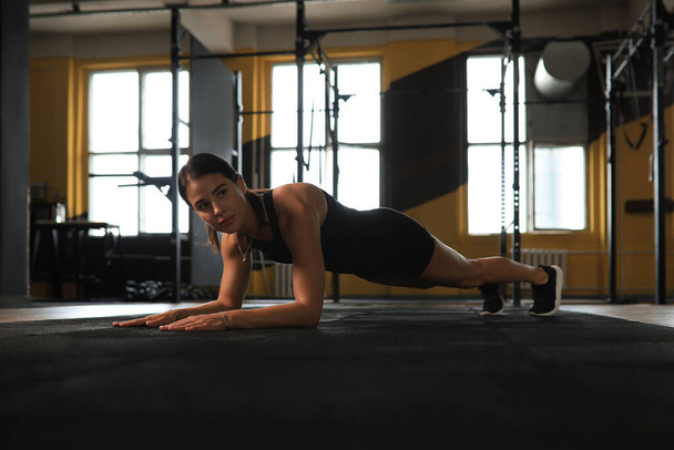 Portrait of a muscular woman on a plank position - Valokuva, kuva