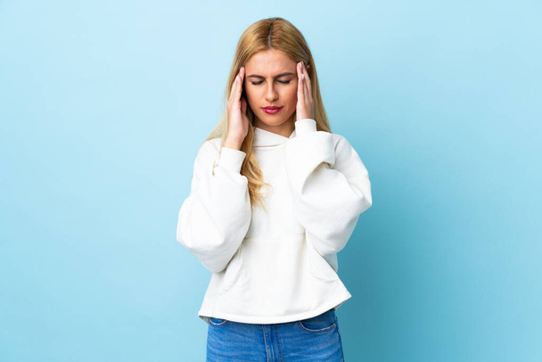 Młoda urugwajska blondynka na odizolowanym niebieskim tle z bólem głowy - Zdjęcie, obraz