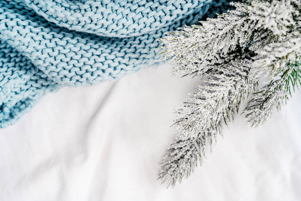 Przytulny zimowy pomysł z gałązką świerkową na łóżku z białym prześcieradłem i kocem. Boże Narodzenie rano - Zdjęcie, obraz
