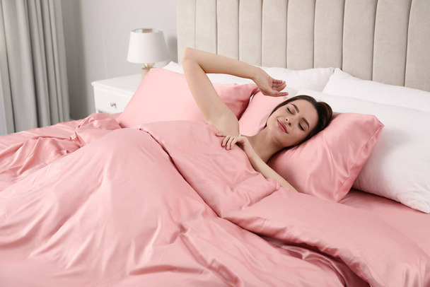 Young woman awaking in comfortable bed with silky linens - Foto, Imagem