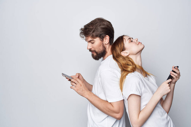 una familia joven pareja con teléfonos en mano comunicación luz fondo - Foto, Imagen
