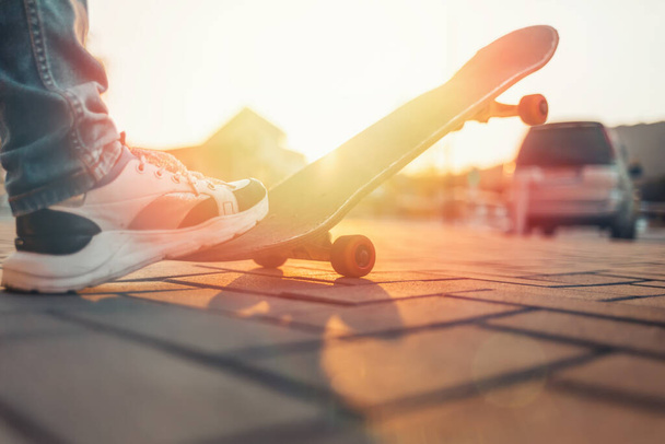 スケートボード。男はスケートボードに足をかけた。閉めろ。日没. - 写真・画像