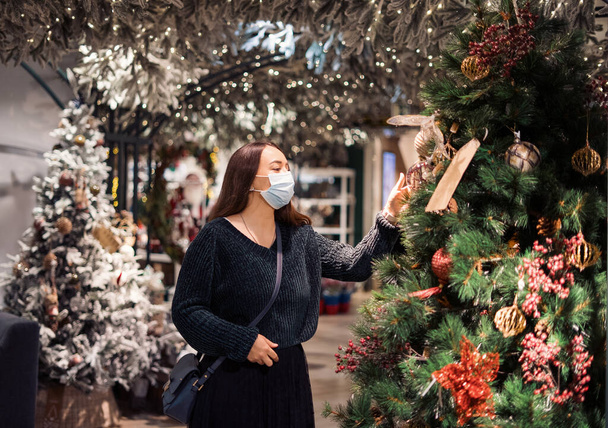 Mulher em máscara facial fazendo compras de Ano Novo em vendas sazonais em mega shopping durante o surto de covid19 - Foto, Imagem