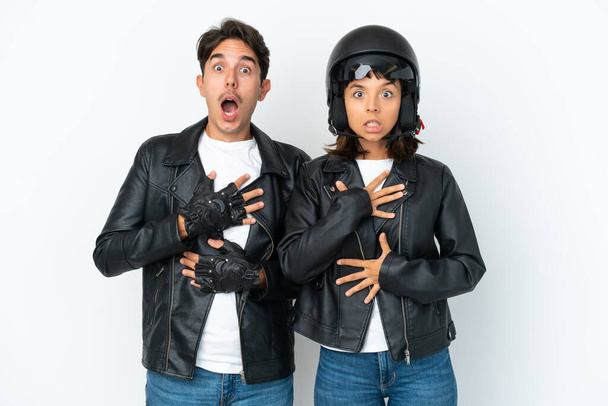 Young mixed race couple with a motorcycle helmet isolated on white background surprised and shocked while looking right - Photo, Image