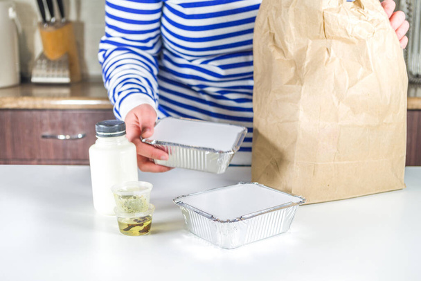 Mulher caucasiana desmontar pacote com caixas de refeição de calor e comer do restaurante. Conceito de comida de serviço de entrega de ordem de retirada, close-up - Foto, Imagem