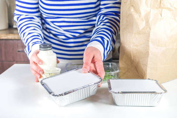 Kaukasische Frau zerlegt Paket mit Heat- and-eat-Essensboxen aus dem Restaurant. Imbiss-Lieferservice-Konzept, Nahaufnahme - Foto, Bild