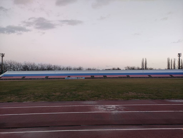 Running tracks and tribunes in the stadium in the evening in winter - Photo, Image