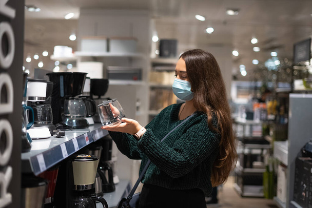 Mulher na máscara escolhendo panela de café - Foto, Imagem
