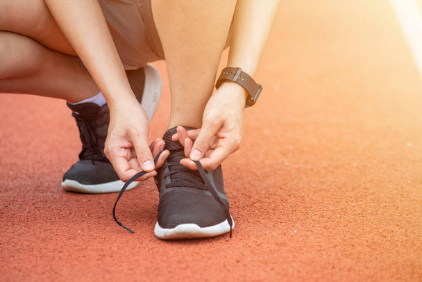 Close up of runner woman tying shoelaces. Conceptual of woman getting ready for jogging in the running track. - 写真・画像