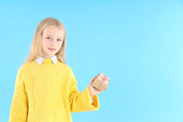 Cute little girl holds gift box on blue background - Fotó, kép