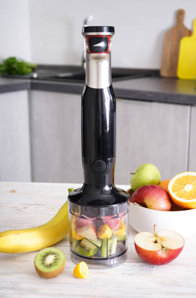 Hand blender for mixing organic raw fresh fruits for making vitamin diet smoothie, healthy food. Vertically. - Фото, изображение