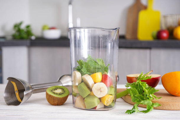 Ручной блендер для смешивания органических свежих фруктов для приготовления витаминного диетического смузи, здоровой пищи. Электрический миксер - Фото, изображение