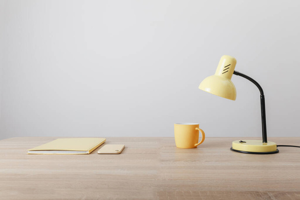 éléments jaunes bloc-notes tasse et lampe sur table en bois - Photo, image