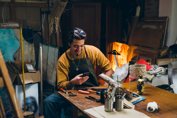 man using smartphone in his workshop - Фото, зображення