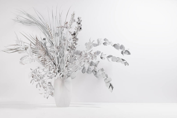 White elegant bouquet of dry leaves, herb, plant in glass vase in soft light modern interior on wood table, copy space. - Foto, Bild