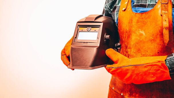A welder in a protective suit, wearing gloves, holding a welding mask under his arm. Close-up, Space for text, Fiery Colors - Foto, immagini