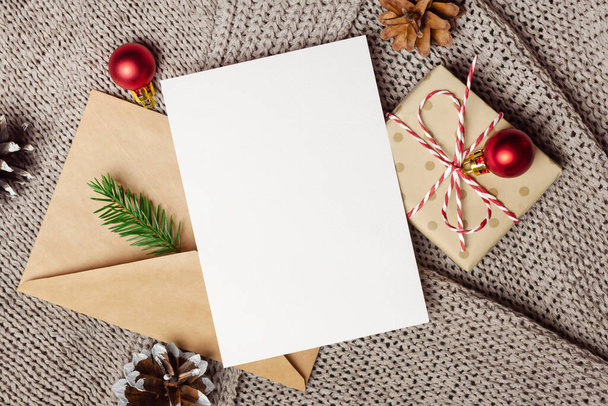 Christmas or New Year greeting card mockup with gift box, envelope and festive decorations, top view - Foto, afbeelding
