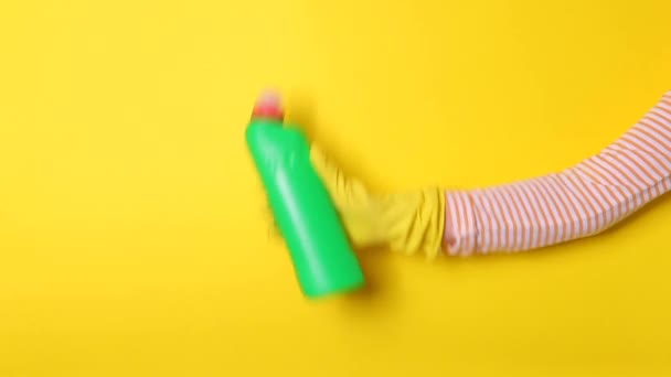 Cepillo y desinfectante en manos femeninas con guantes sobre fondo de color - Imágenes, Vídeo