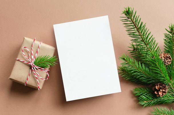 Kerstkaart mockup met geschenkdoos en dennenboom takken met kegels - Foto, afbeelding