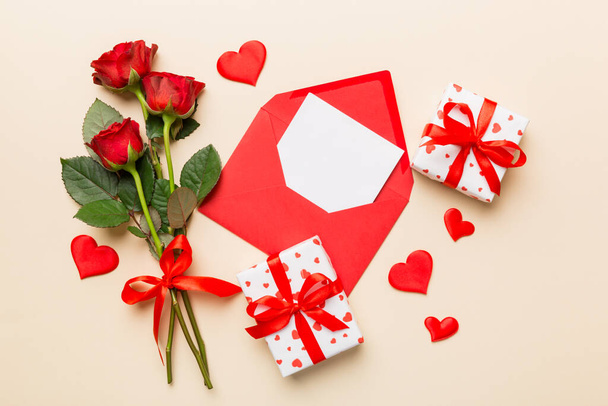 Ystävänpäivä koostumus kirjekuori, ruusu kukka ja punainen sydän pöydällä. Ylänäkymä, tasainen. Loma-ajatus. - Valokuva, kuva