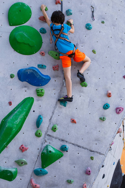 少年は登山の壁に登る。アウトドアクライミングトレーニング. - 写真・画像