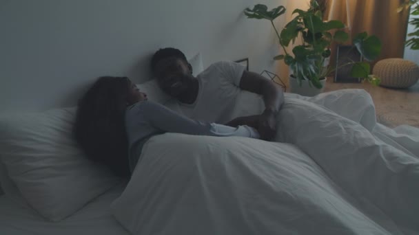 Familie communicatie. jong gelukkig Afrikaans amerikaans paar in liefde dragen pyjama 's met elkaar praten, liggend in bed - Video