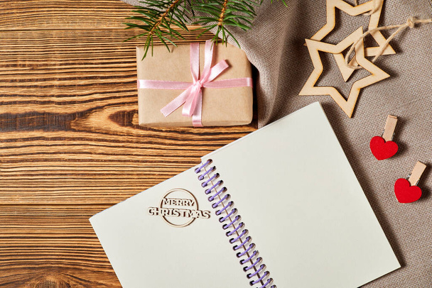 Κενό σημειωματάριο στο φόντο του δώρου, ξύλινα αστέρια και το νέο έτος δέντρο σε ξύλινο φόντο - Φωτογραφία, εικόνα