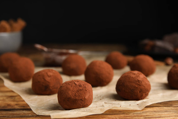 Delicious chocolate truffles powdered with cocoa on wooden table, closeup. Space for text - Fotoğraf, Görsel