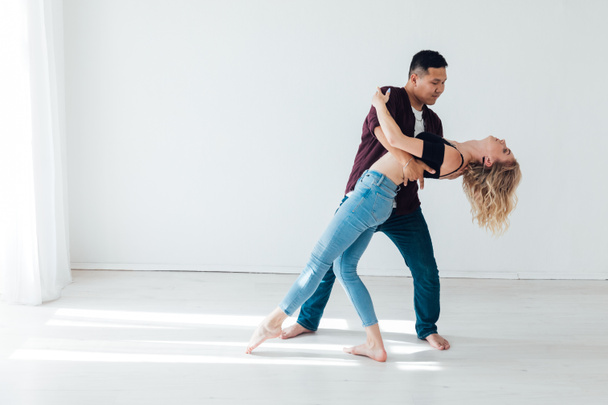 a woman and a man dancing to the music of a bachata in a white hall - Photo, Image