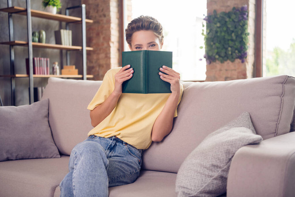 Photo of adorable childish young lady wear yellow t-shirt book cover face indoors room home - Φωτογραφία, εικόνα