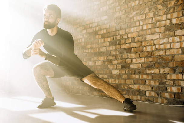 Confident mid aged white sportsman exercising in a bright room doing lunges - Fotoğraf, Görsel