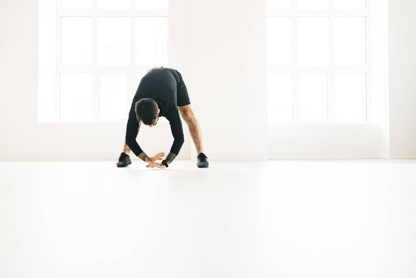 Confident mid aged white sportsman exercising in a bright room stretching - Fotoğraf, Görsel
