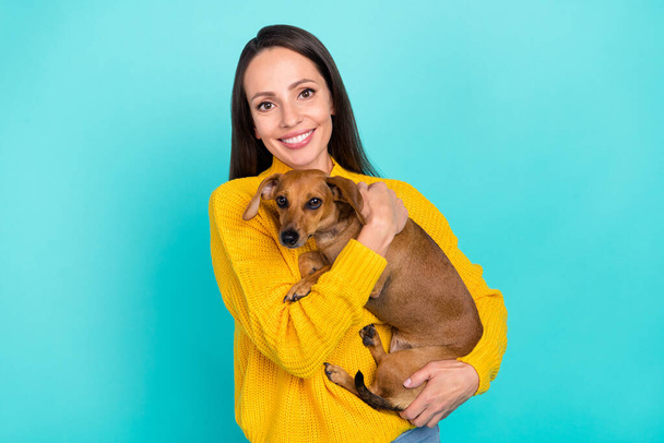 Portrait of attractive cheerful girl veterinarian carrying in hands doggy isolated over bright teal turquoise color background - Photo, image