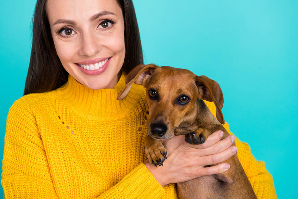 Cropped view portrait of attractive cheerful careful girl holding puppy vet isolated over bright teal turquoise color background - Fotó, kép