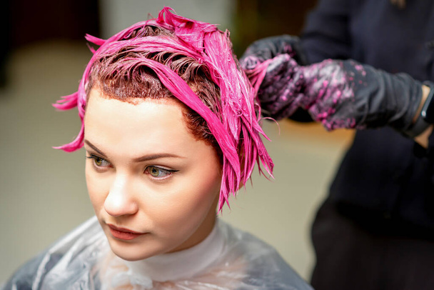 Le coiffeur professionnel utilise un pinceau pour appliquer le colorant rose sur les cheveux. Concept de coloration des cheveux
 - Photo, image