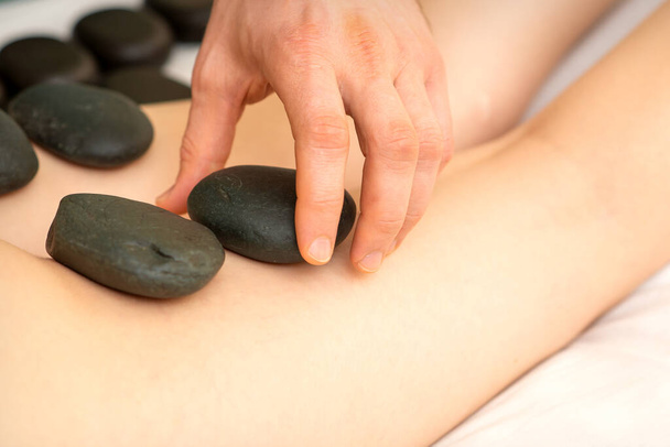Μια γυναίκα να πάρει spa hot πέτρα θεραπεία πόδια μασάζ διαδικασία σε ένα σαλόνι ομορφιάς - Φωτογραφία, εικόνα