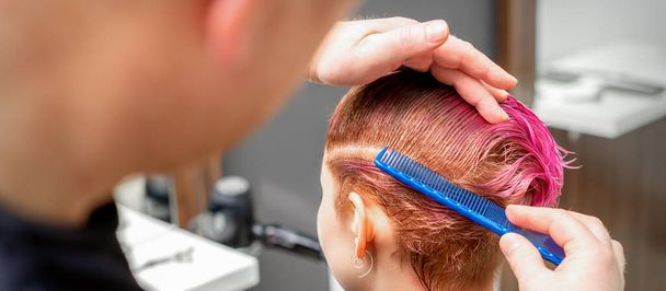 Розчісування волосся молодої жінки під час фарбування волосся в рожевий колір в перукарні крупним планом
 - Фото, зображення